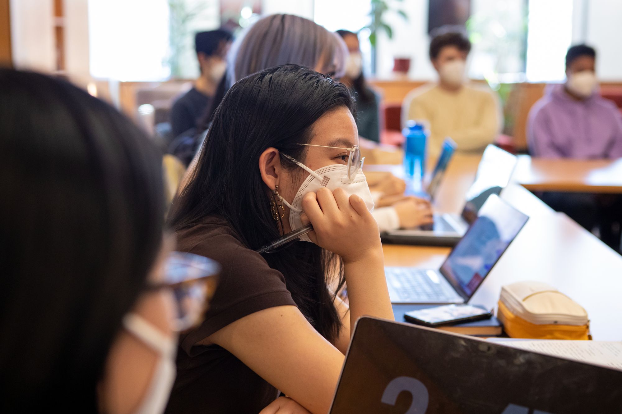 The image depicts a student at a desk listening in on the talk, focusing intently.