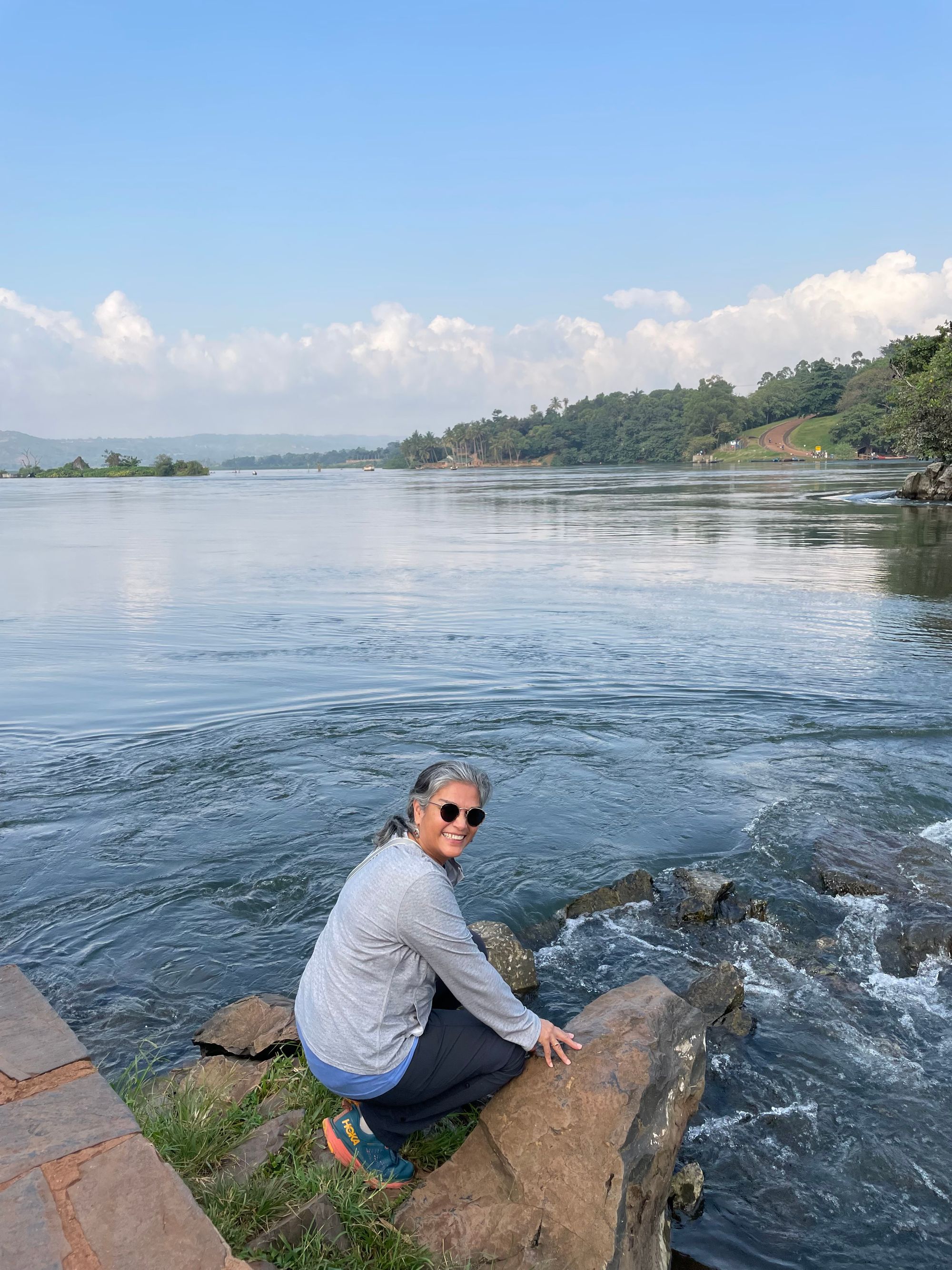 Ahluwalia crouching and smiling near the bank of a lake.