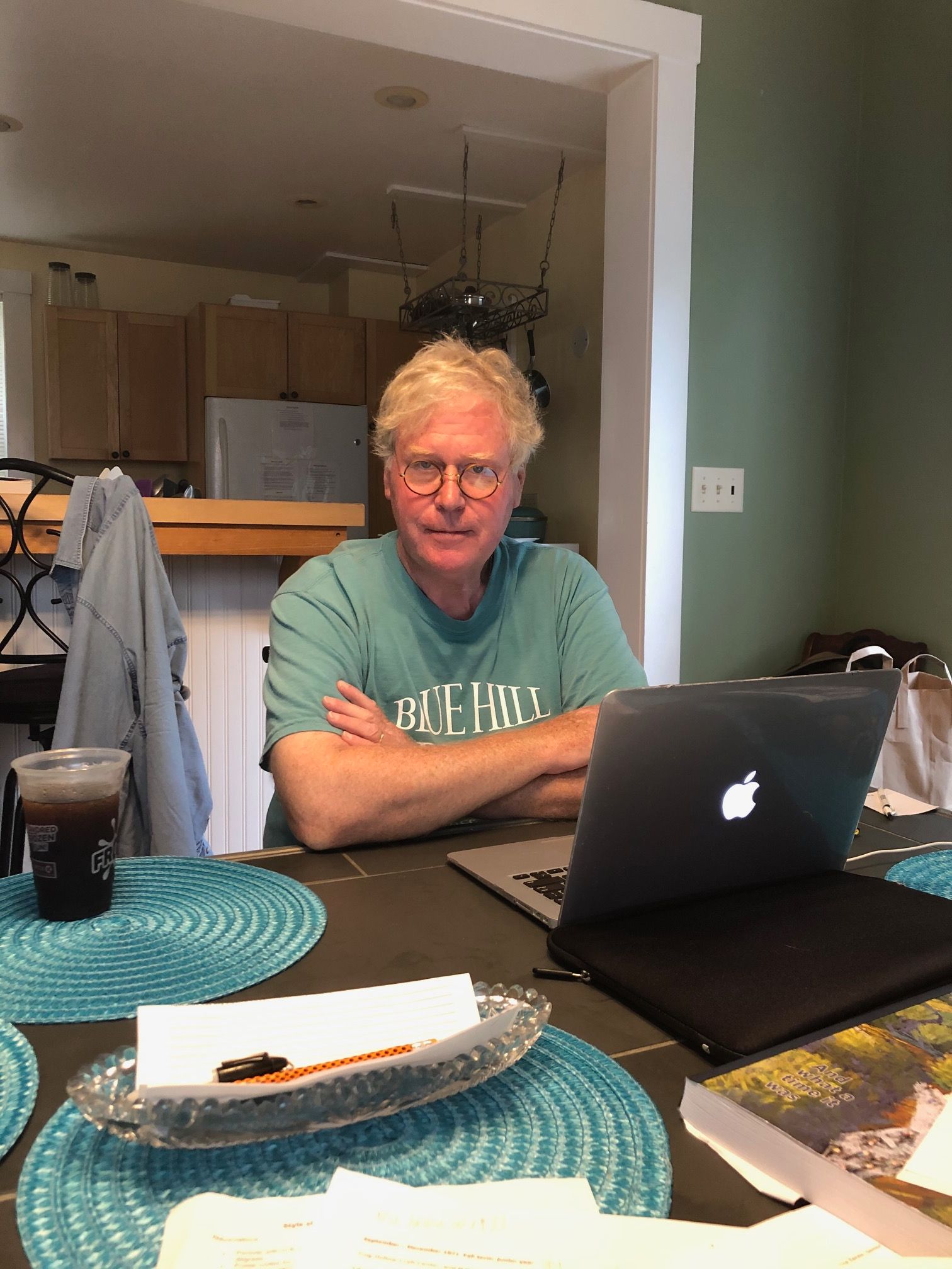 Murphy sitting at the table with his laptop, arms crossed, and looking over his glasses at the camera.